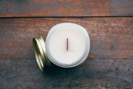 top view of a white woodwick candle with wood background